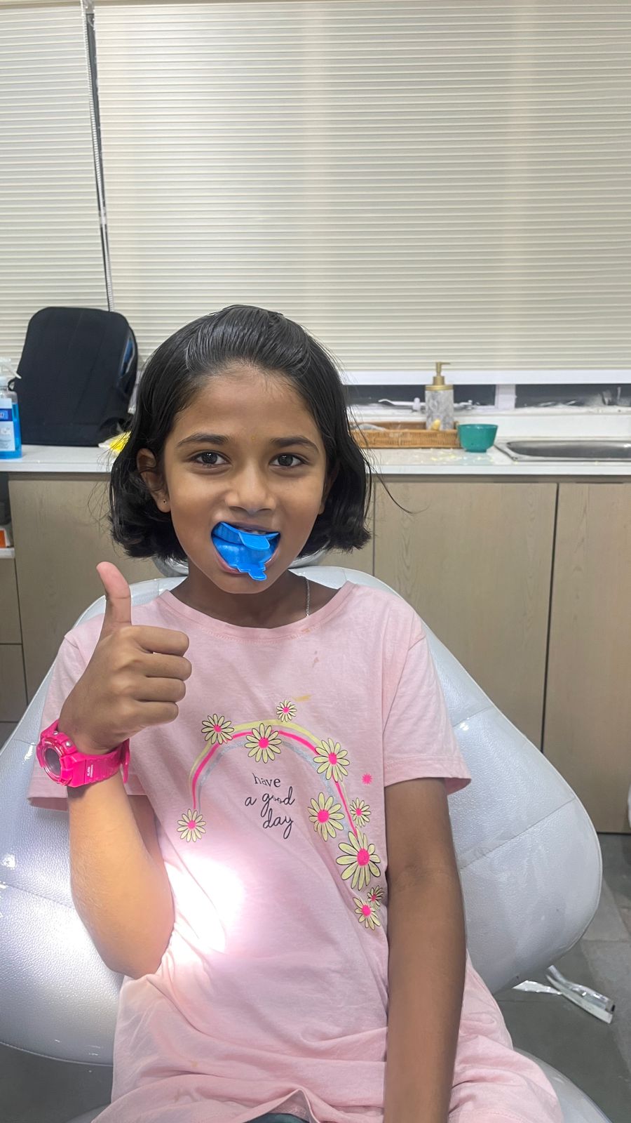 Child with a fluoride tray in place, giving a thumbs up